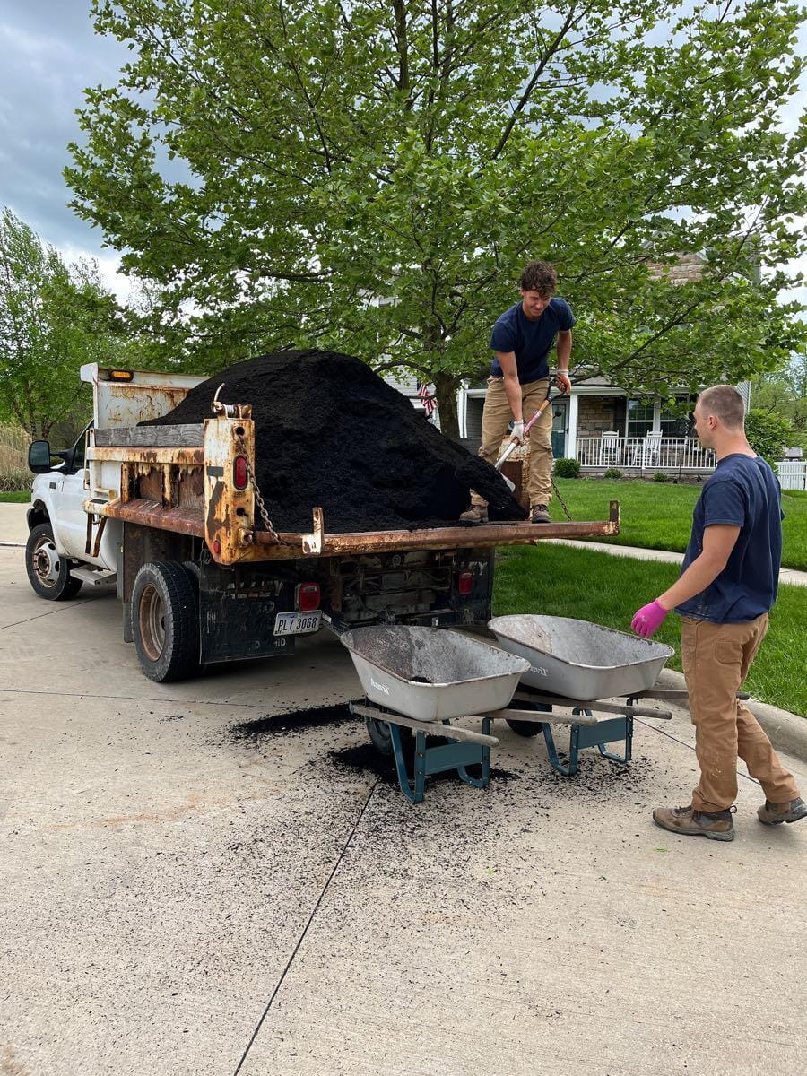 DK Outdoor Services crew shoveling mulch from the company dump truck into wheelbarrows