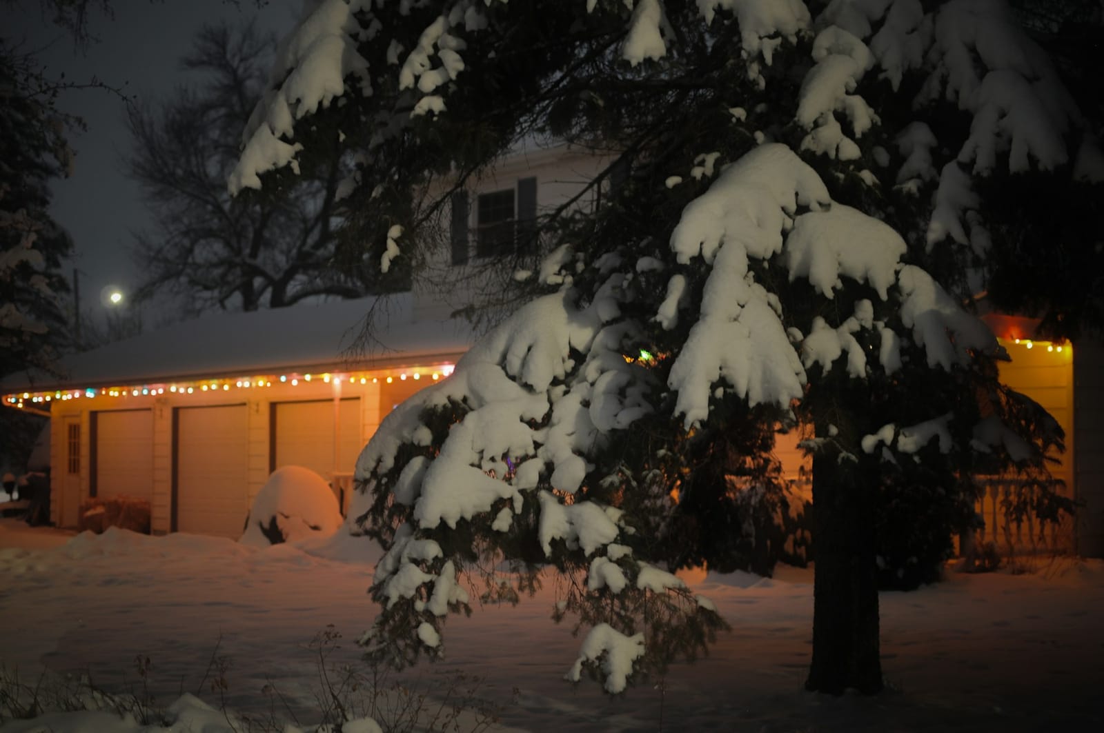 Snowy garage with multicolor Christmas lights on the roofline