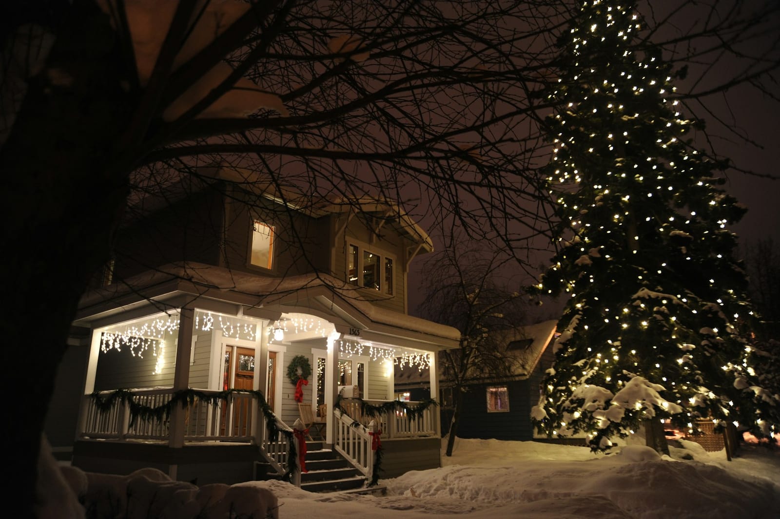 Snowy porch with icicle lights and a lit pine tree